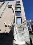 Escultura blanca moderna frente a edificio del Dairy Block bajo cielo azul