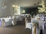 Sala interior preparada para eventos con mesas cubiertas y sillas decoradas