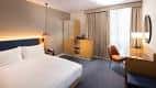 Interior de una habitación estándar del hotel con cama doble, mobiliario moderno y decoración neutra