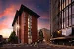Fachada del Hilton Garden Inn Birmingham Brindleyplace al atardecer con iluminación ambiental y entorno urbano