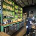 Interior del establecimiento mostrando las estanterías verdes con botellas y la barra