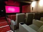 Interior de la sala de proyección con butacas modernas y pantalla iluminada en rosa