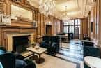 Interior del vestíbulo principal con decoración clásica, chimenea y lámparas de cristal