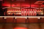 Bar principal con letrero 'DRINKS' iluminado en rojo
