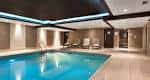 Piscina interior moderna con zona de descanso y iluminación ambiental