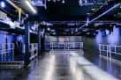 Interior del espacio de eventos con iluminación azul y estructura industrial