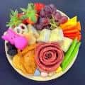 Plato de aperitivos con frutas, quesos y carnes en presentación artística