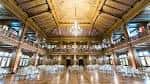 Salón de eventos preparado para recepción con mesas blancas y techo alto