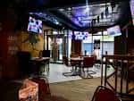 Interior del OZ Bar con mesas y pantallas de televisión