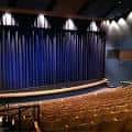 Interior del auditorio con cortinas azules y iluminación escénica