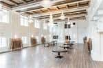 Espacio interior versátil con suelo de madera y vigas expuestas, listo para configuraciones múltiples