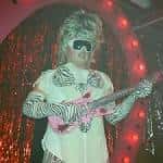 Escenario con artista tocando la guitarra bajo luces rojas