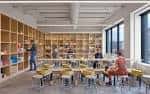 Sala de talleres o clases con mesas, sillas y estanterías llenas de materiales