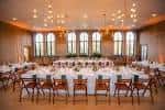 Sala de eventos decorada para una boda con mesas redondas y arcos de ventanas