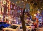 Fachadas de edificios históricos de ladrillo con iluminación navideña y árboles adornados