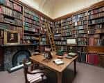 Sala de lectura con estanterías llenas de libros y una escalera de madera