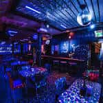 Interior de Distrikt Bar con mesas, barra y bola de discoteca
