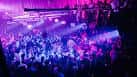 Multitud bailando en el interior del club con luces púrpuras