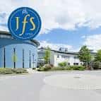 Fachada frontal de JFS School con logotipo circular y entorno paisajístico