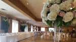 Salón de eventos decorado con mesas blancas y centro floral grande
