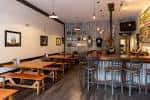 Interior del bar de Hop Farm Brewing Company con mesas de madera y barra