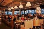 Interior del restaurante Indaco con mesas ocupadas y lámparas colgantes