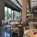 Área de comedor con mesas redondas y grandes ventanales