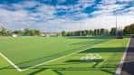 Campo de fútbol con césped artificial bajo cielo azul