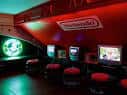 Zona de juegos retro con pantallas iluminadas y sillas rojas en el Four Quarters