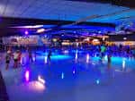 Pista de patinaje nocturna con iluminación azul y personas patinando