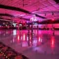 Ambiente festivo en la pista con iluminación rosa y patinadores