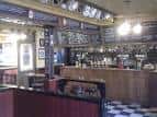 Interior del pub Fat Cat & Canary con barra de madera y azulejos en el suelo