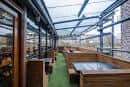 Terraza cubierta con asientos tipo booth y estructura metálica