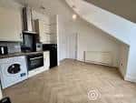 Cocina moderna en ático con suelo de parquet y armarios blancos