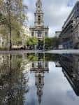 Reflejo de la iglesia en una fuente o charco frente al edificio