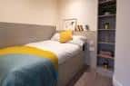 Habitación individual amueblada con cama y estantería