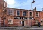 Fachada principal del pub The Midnight Bell en Leeds con letrero visible