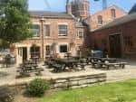 Área exterior del pub con mesas y sillas bajo el sol