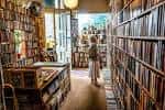 Interior acogedor de la librería con estanterías llenas de libros y una persona caminando entre los pasillos