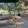 Área de picnic con mesas y parrillas bajo techado en el parque