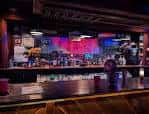 Interior del bar con barra de madera y luces de neón