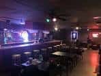 Salón principal con mesas, taburetes y ambiente nocturno
