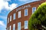 Fachada exterior del edificio John Lewis en Norwich con cielo azul y árboles