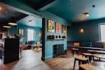 Interior del bar Over The Yardarm con paredes azules y mesas