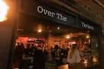 Entrada nocturna del bar Over The Yardarm con ambiente interior visible