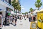 Mercado al aire libre en Midtown Tampa con puestos y palmeras bajo el sol