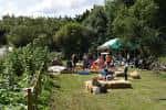 Vista general de un evento al aire libre en Kirkstall Valley Farm con personas reunidas y toldos verdes