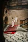 Interior del vestíbulo con escalera de mármol, alfombra roja y pareja en ceremonia