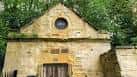 Fachada frontal del edificio histórico con ventana circular y puerta de madera