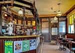 Interior tradicional del pub con barra de madera, lámparas colgantes y mesas